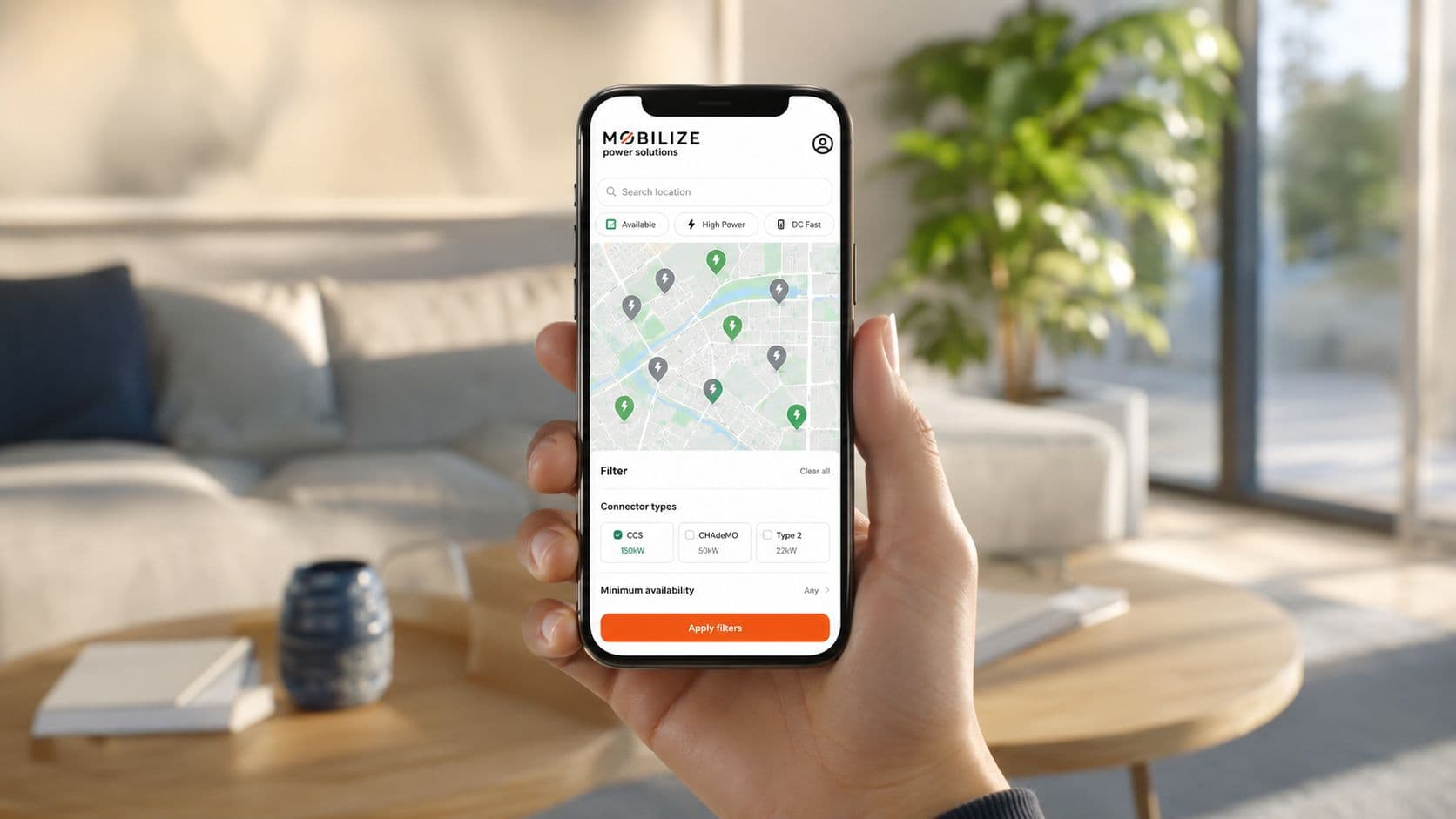 Una mano sosteniendo un teléfono inteligente mostrando la aplicación Mobilize Power Solutions con un mapa de carga.